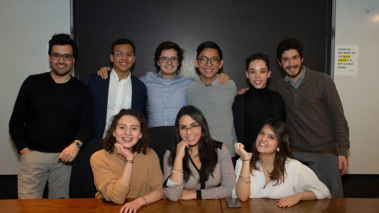 Image of 9 people posing in semi formal attire, a professionally taken image