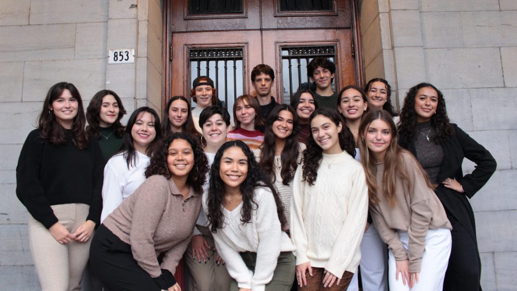 Image of various individuals posing in front of an antique doorway smiling at the camera